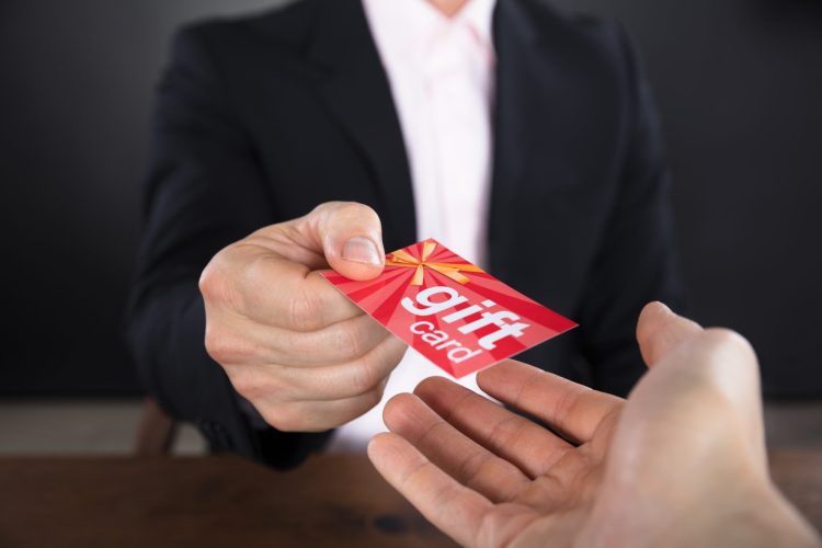 Close-up Of A Businessperson Hands Giving Gift Card To Other Businessperson